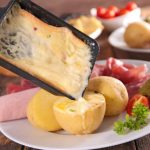 raclette cheese melting with potato, salami and ham